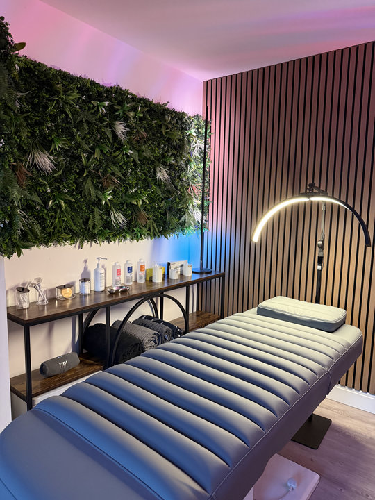 A closer view of the sculptural treatment lamp, green wall and upholstered treatment bed