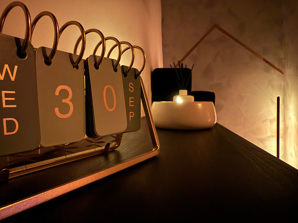 A brass flip calendar and candle in the warm amber light of the massage room